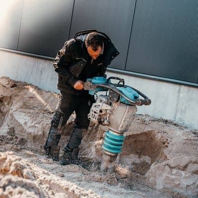 Medewerker van Dorrestijn verdicht zand met een trilstamper