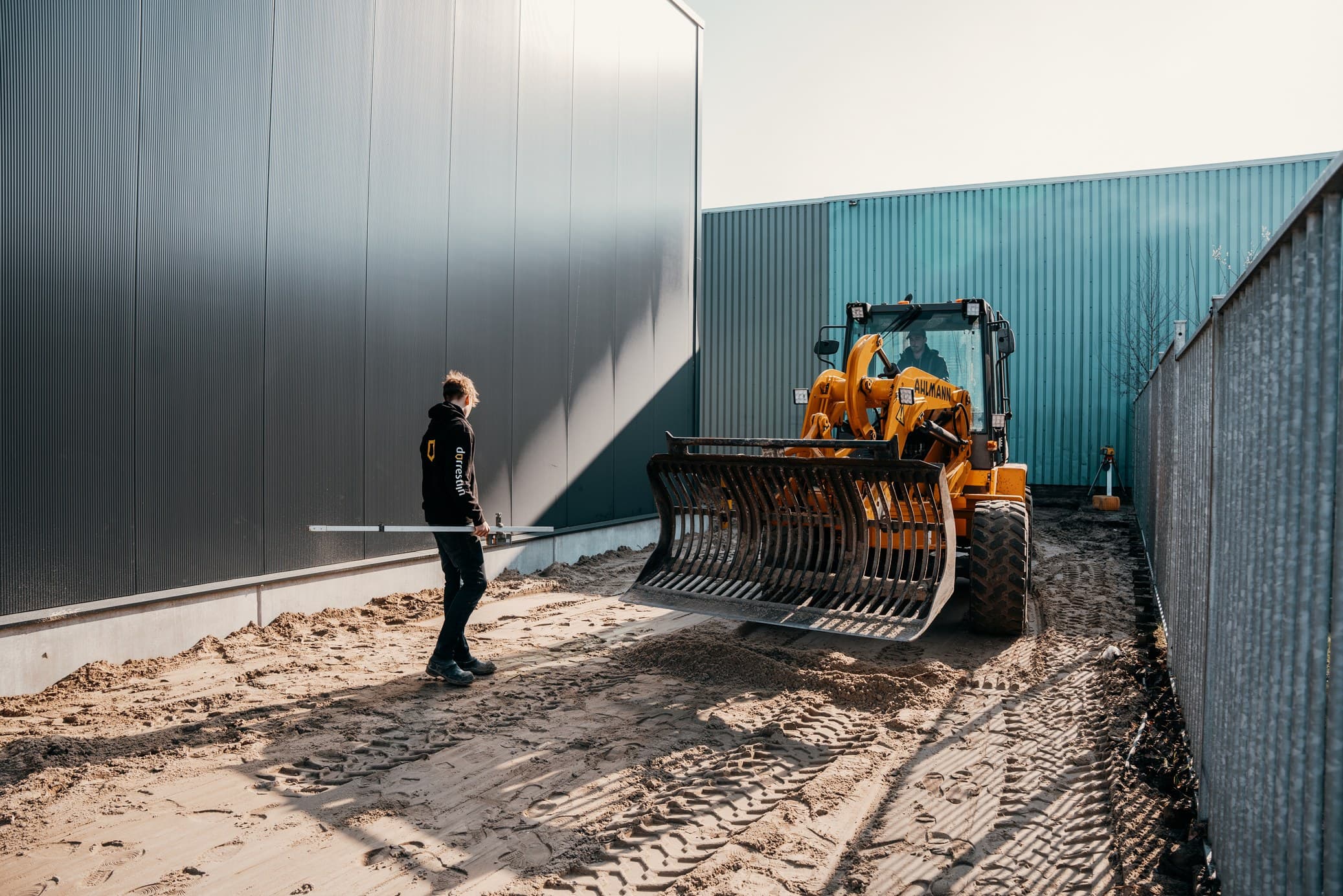 Shovel en medewerker op een bouwrijp bedrijfsterrein